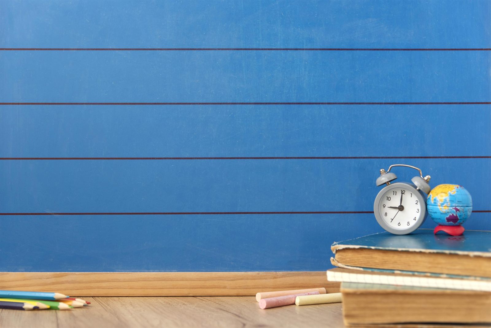 Notebooks, pencils, and a globe on a blue desk